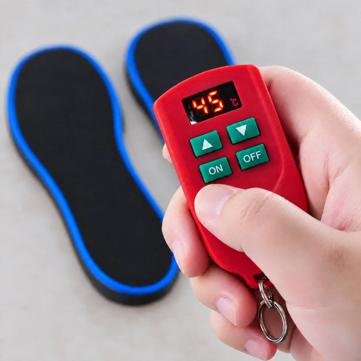 Rote Fernbedienung mit Temperaturanzeige in °C und den Tasten ▲, ▼, ON und OFF in der Hand