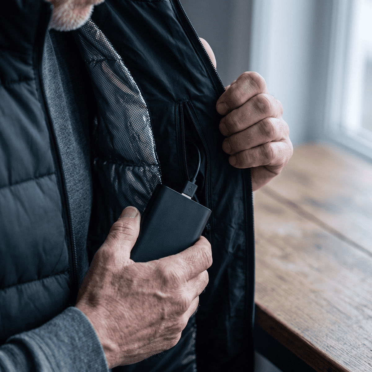 Powerbank wird in die Innentasche der Heizweste gesteckt