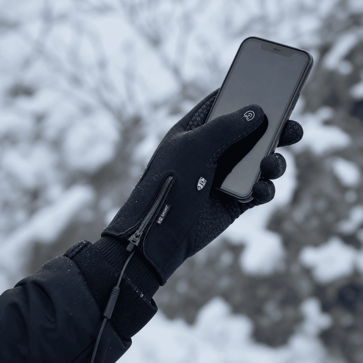 Behandschuhte Hand bedient ein Smartphone im Schnee